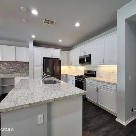 a kitchen with stainless steel appliances granite countertop a sink stove microwave and refrigerator