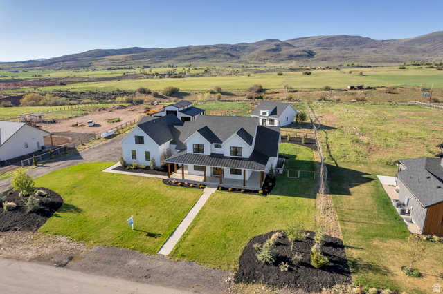 1820 West Farmhouse Flats Road Peoa, UT 84061 - Photo 4 of 79 Modern farmhouse-style residence featuring a white exterior, black roof, and covered front porch with natural wood columns