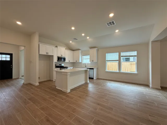 a large kitchen with kitchen island a sink wooden floor and a refrigerator