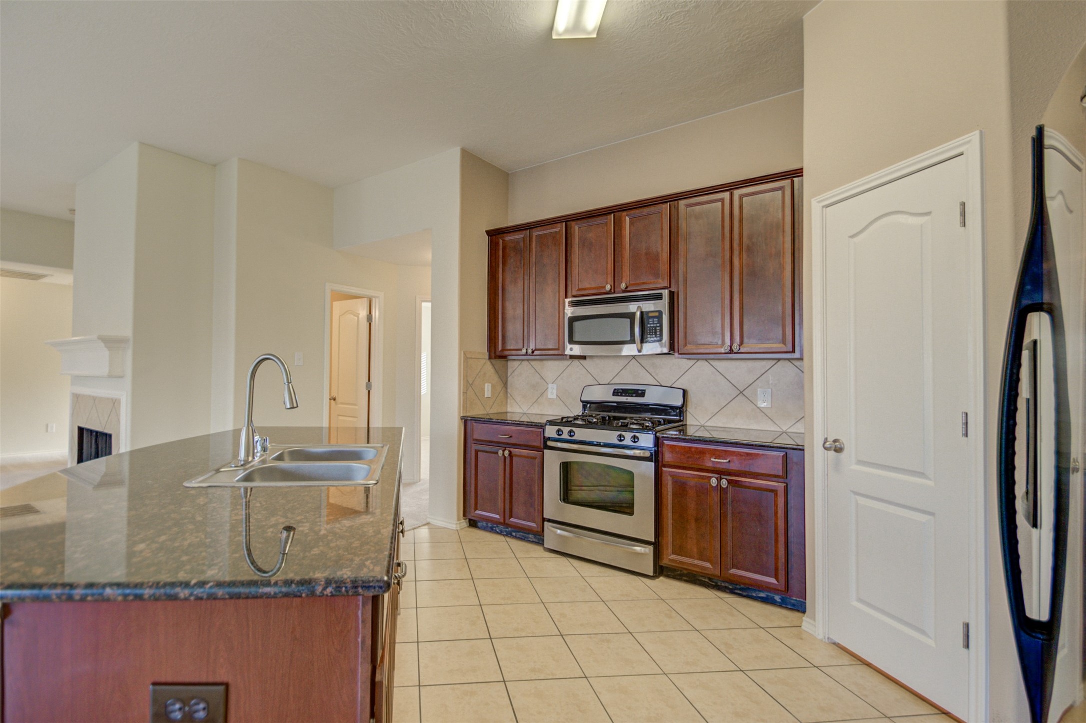 2406 Grove View Trail Fresno, TX 77545 - Photo 5 of 17 a kitchen with granite countertop a stove sink and microwave