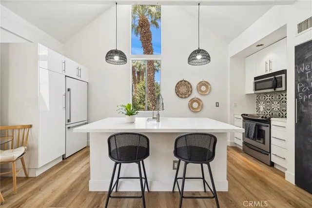 a kitchen with stainless steel appliances a dining table chairs and white cabinets