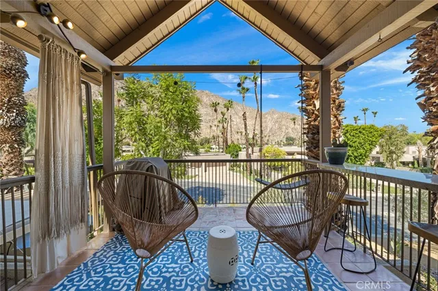 a view of a balcony with chairs and iron fence
