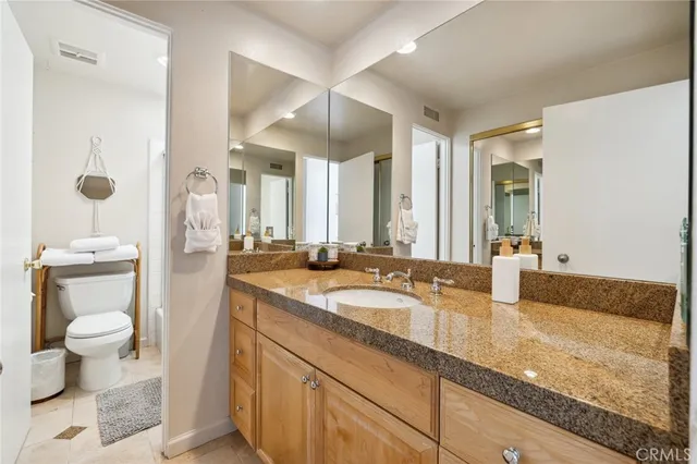 a bathroom with a granite countertop sink a toilet a mirror and shower