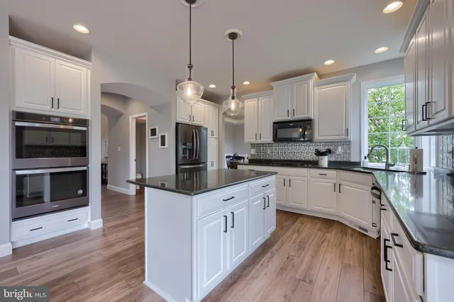a kitchen with stainless steel appliances granite countertop a sink refrigerator and cabinets