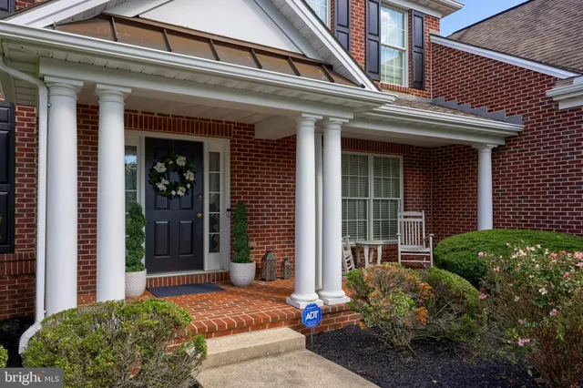 a view of a white house next to a yard with plants and trees