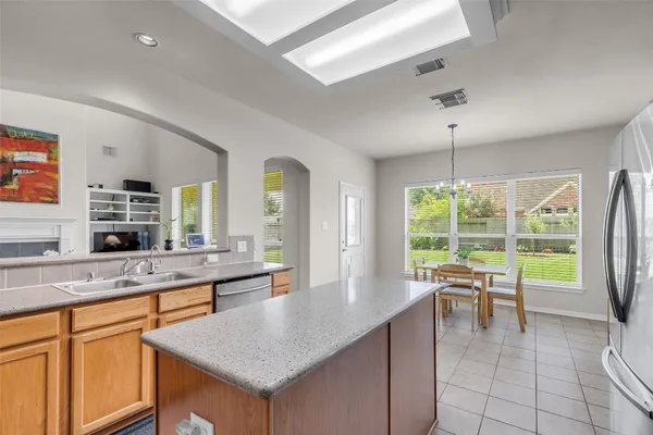 a large kitchen with kitchen island a large window a sink and living room view