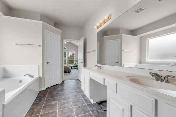 a spacious bathroom with a bathtub sink and mirror