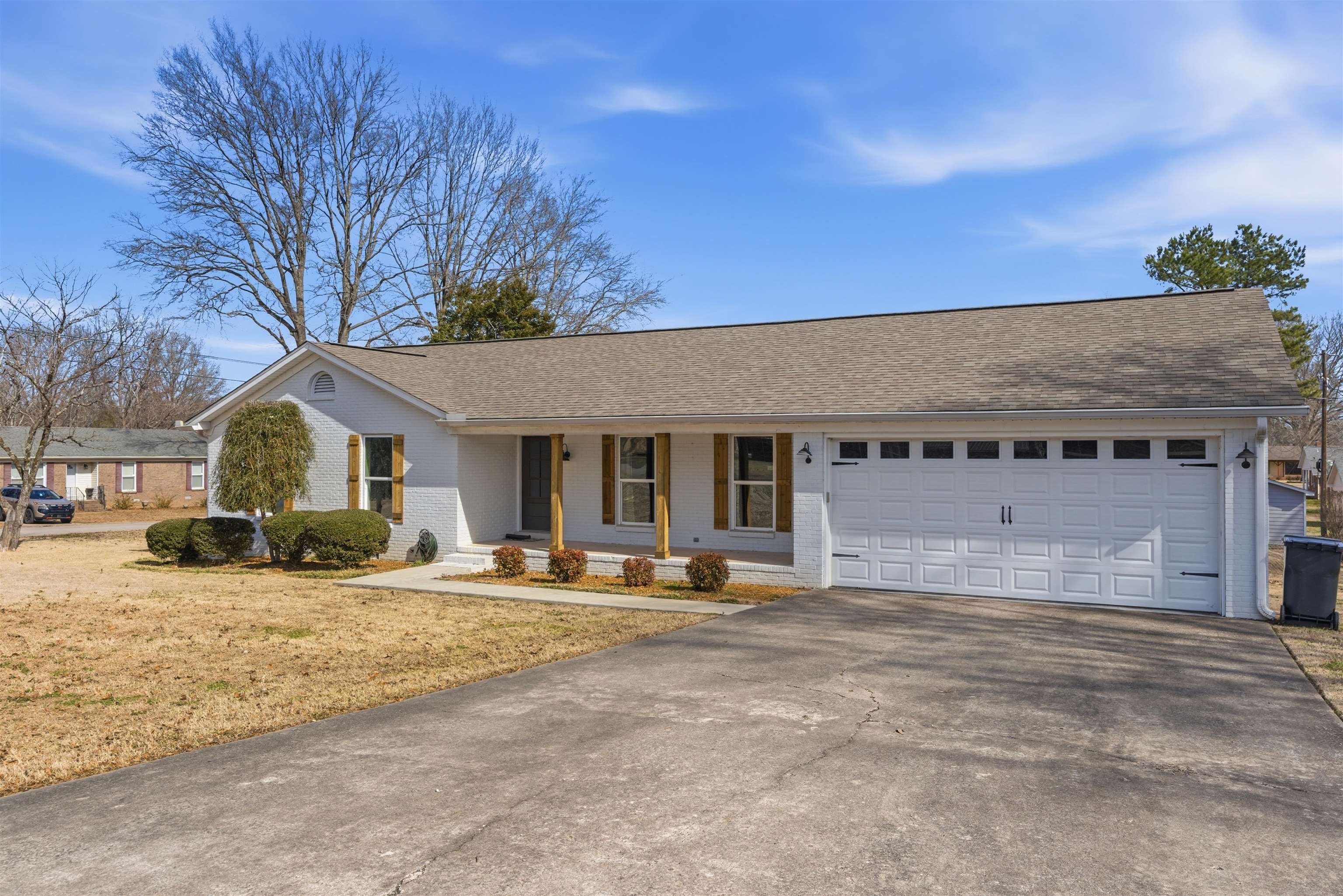 222 Barrett Street Bolivar, TN 38008 - Photo 2 of 30 Single story home featuring a porch, asphalt driveway, brick siding, a garage, and a shingled roof