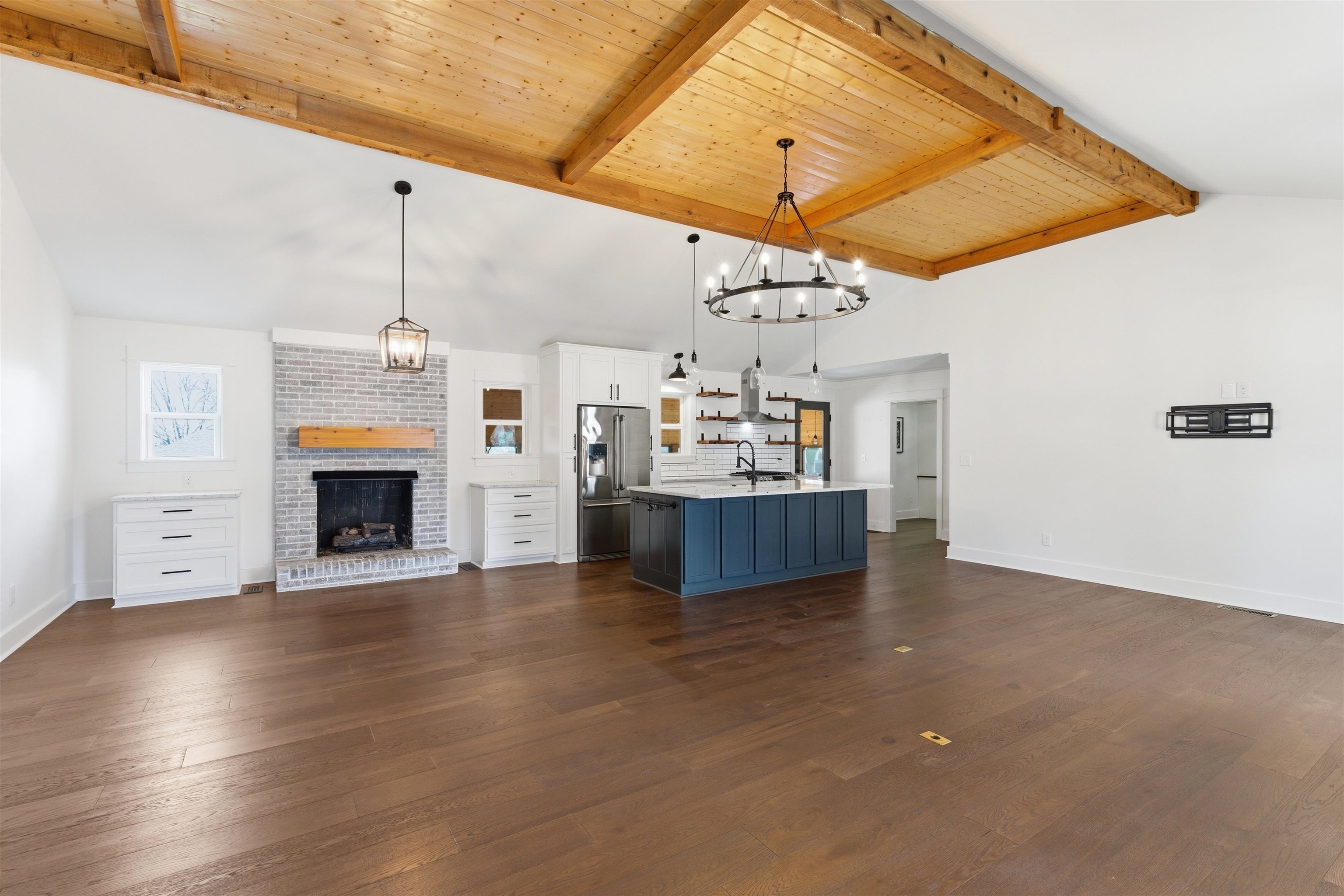 222 Barrett Street Bolivar, TN 38008 - Photo 5 of 30 Unfurnished living room featuring hanging lights, a brick fireplace, dark wood finished floors, and a high wood beamed ceiling