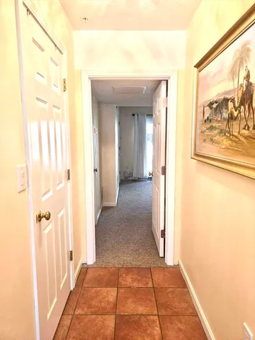 a view of a hallway with wooden floor and a bathroom
