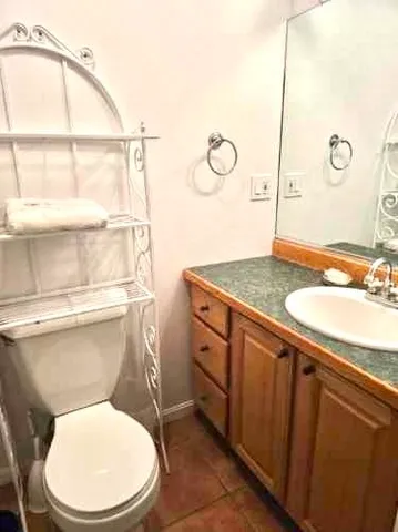 a bathroom with a granite countertop toilet sink and mirror