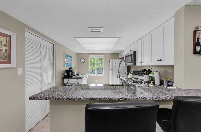 a kitchen with granite countertop kitchen island a sink stove and cabinets