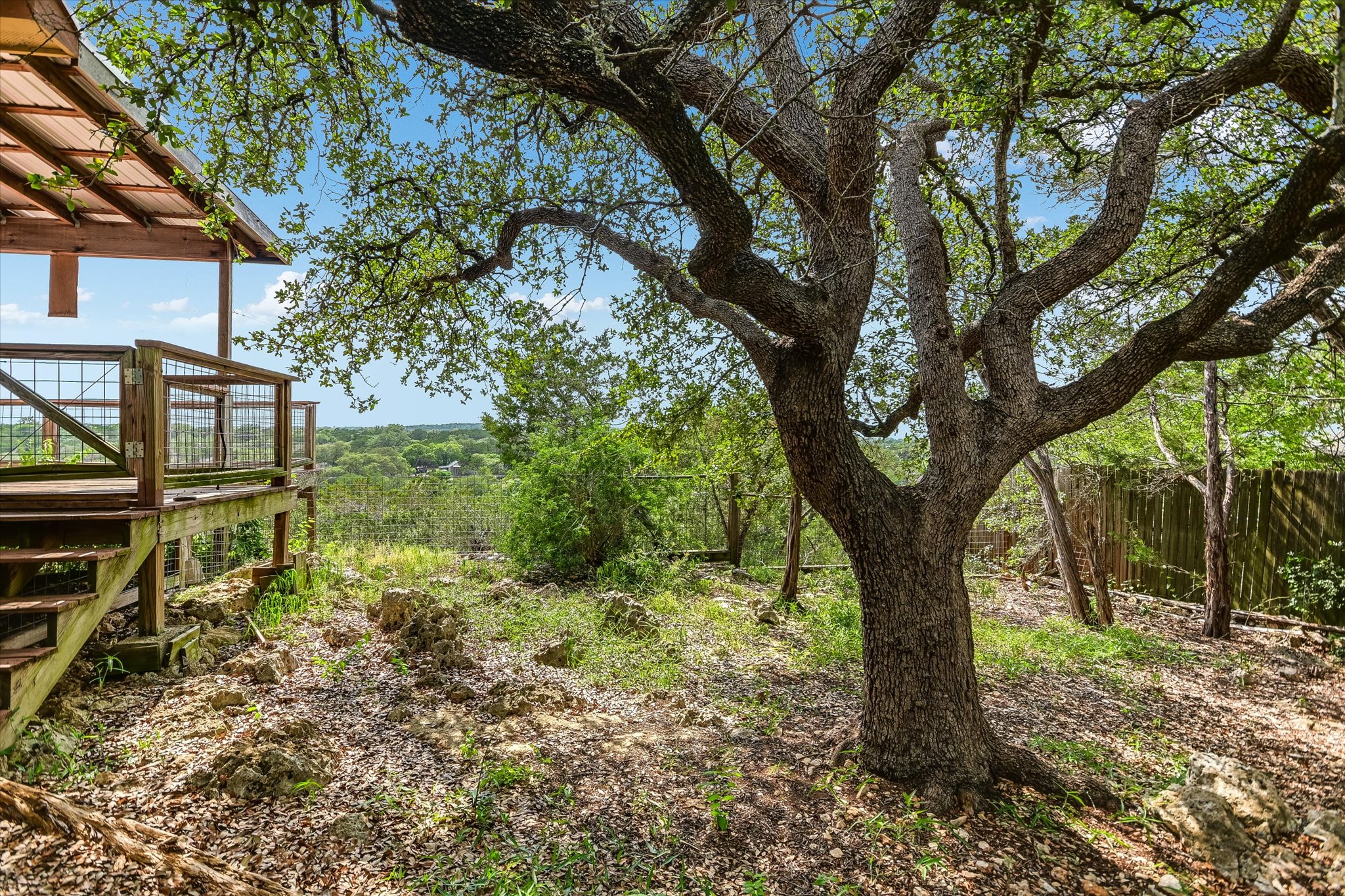 700 Cliffside Road Wimberley, TX 78676 - Photo 16 of 22 Elevated wood deck with metal railing, featuring a covered patio area and exterior stairs