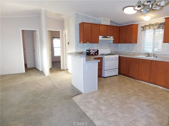 a kitchen with granite countertop a stove top oven a sink dishwasher and a refrigerator with wooden floor