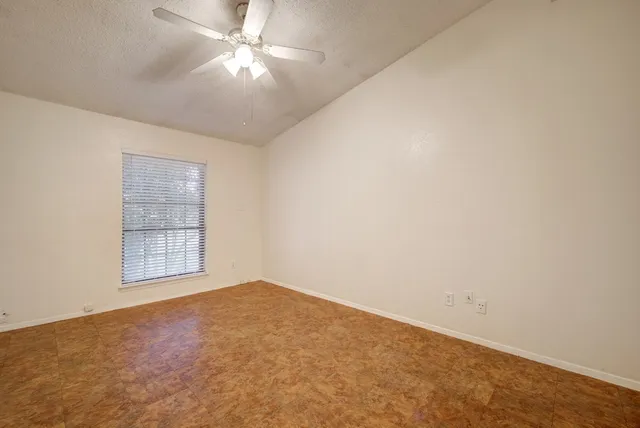 an empty room with windows and fan