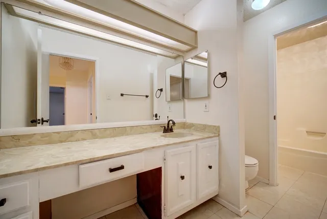 a bathroom with a granite countertop sink a toilet and a mirror
