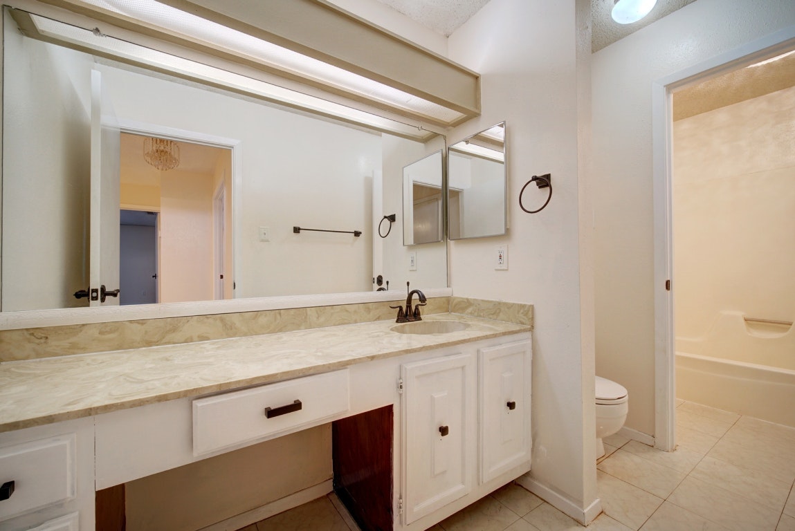 10509 Doering Lane Austin, TX 78750 - Photo 15 of 36 a bathroom with a granite countertop sink a toilet and a mirror