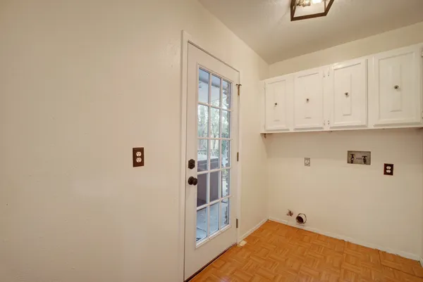 an empty room with a chandelier fan and windows