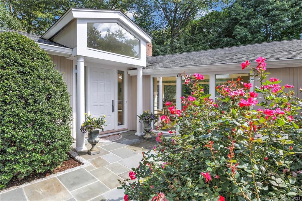 a front view of a house with a lot of flowers and trees