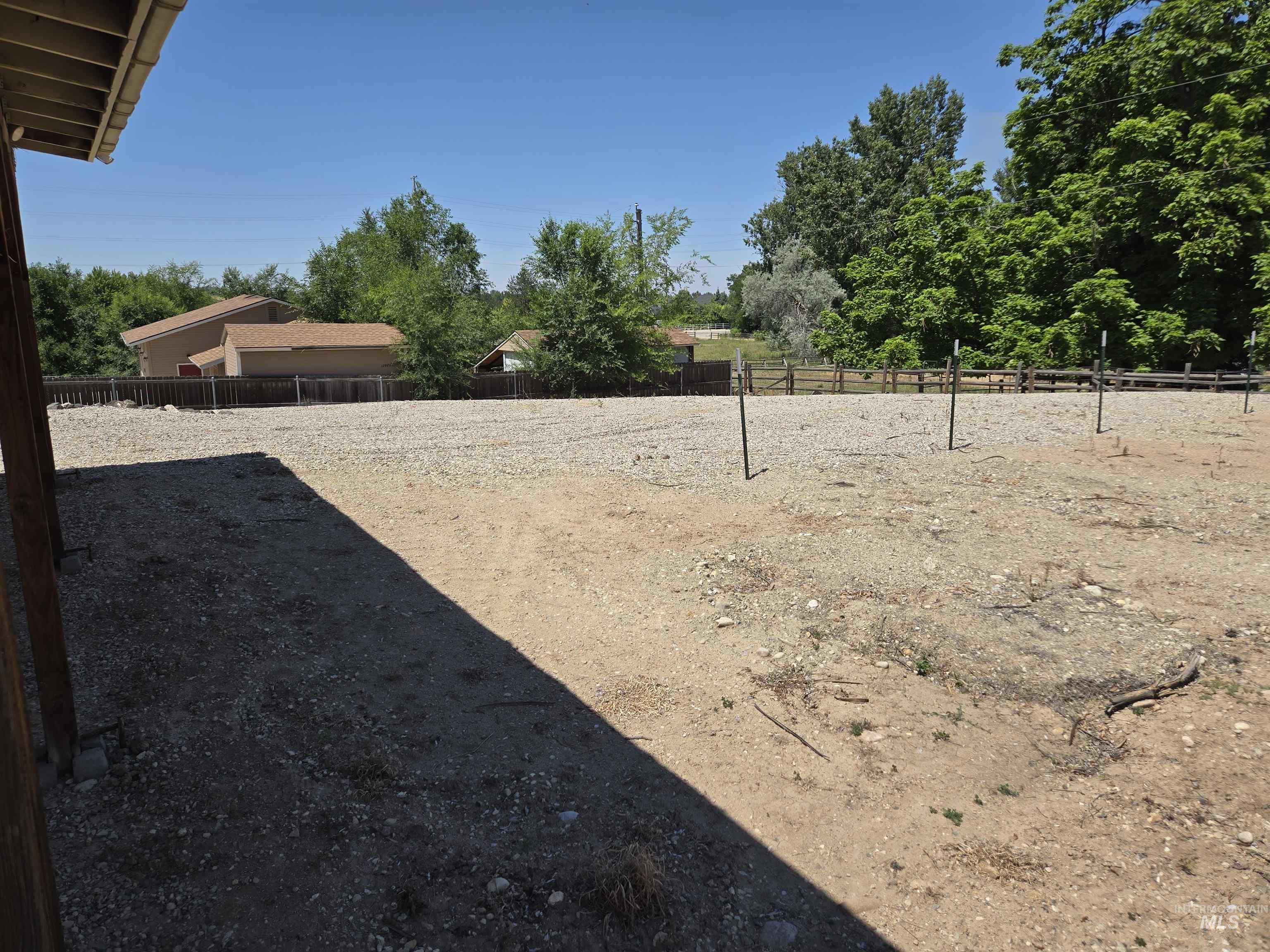 12050 West Hidden Valley Rim Road Boise, ID 83709 - Photo 34 of 39 Expansive gravel and dirt area framed by a wooden fence and mature trees
