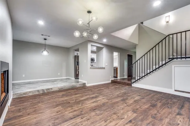 a view of an empty room with wooden floor and a ceiling fan
