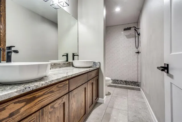 a bathroom with a granite countertop sink a toilet a mirror and shower