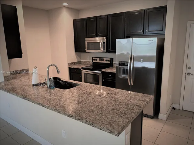 a kitchen with granite countertop a refrigerator and a stove top oven