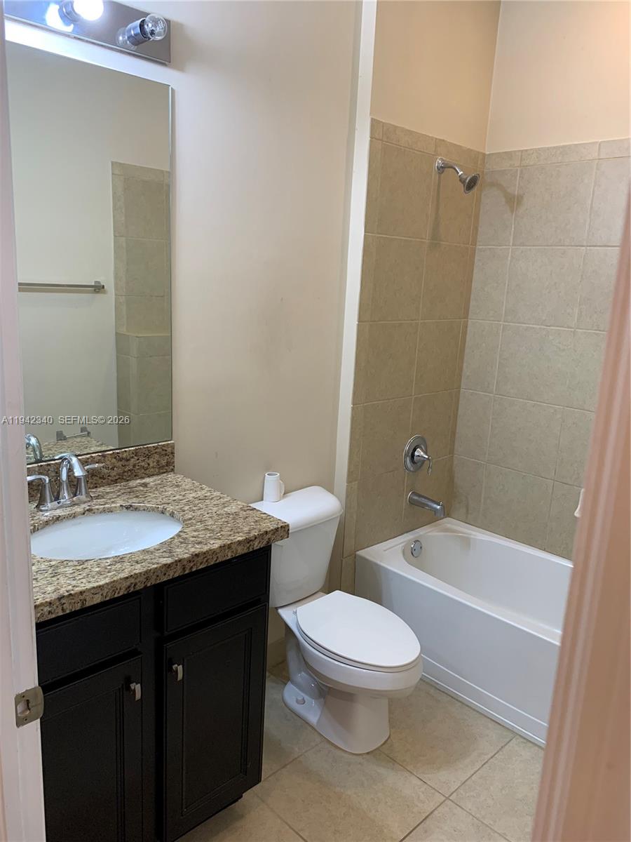 2566 Southwest 119th Way, Unit 3911 Miramar, FL 33025 - Photo 9 of 11 a bathroom with a granite countertop sink a toilet a mirror and shower