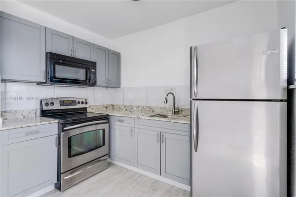 a kitchen with stainless steel appliances granite countertop a refrigerator stove a sink and a microwave