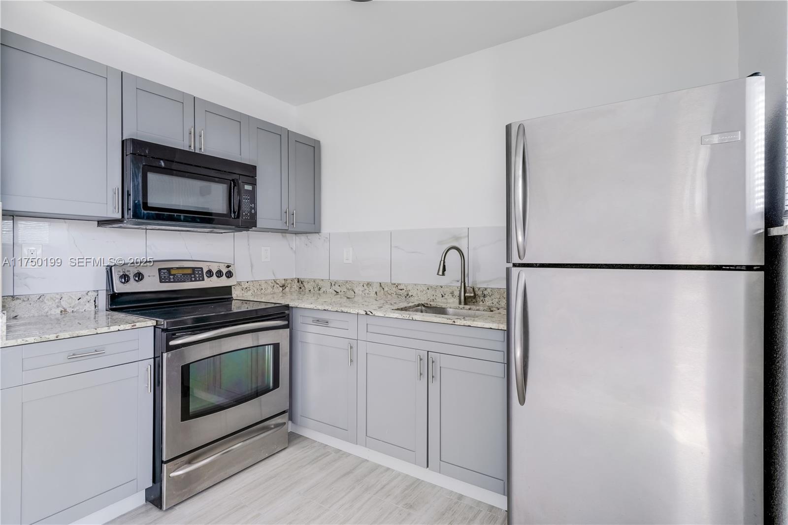 1281 Northwest 61st Street, Unit 2 Miami, FL 33142 - Photo 5 of 13 a kitchen with stainless steel appliances granite countertop a refrigerator stove a sink and a microwave