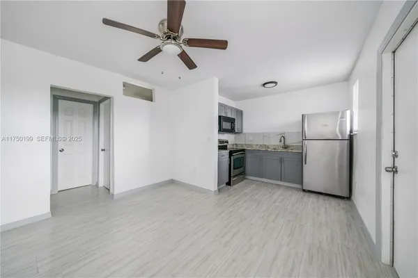 a kitchen with stainless steel appliances a refrigerator a sink dishwasher a stove and white cabinets with wooden floor