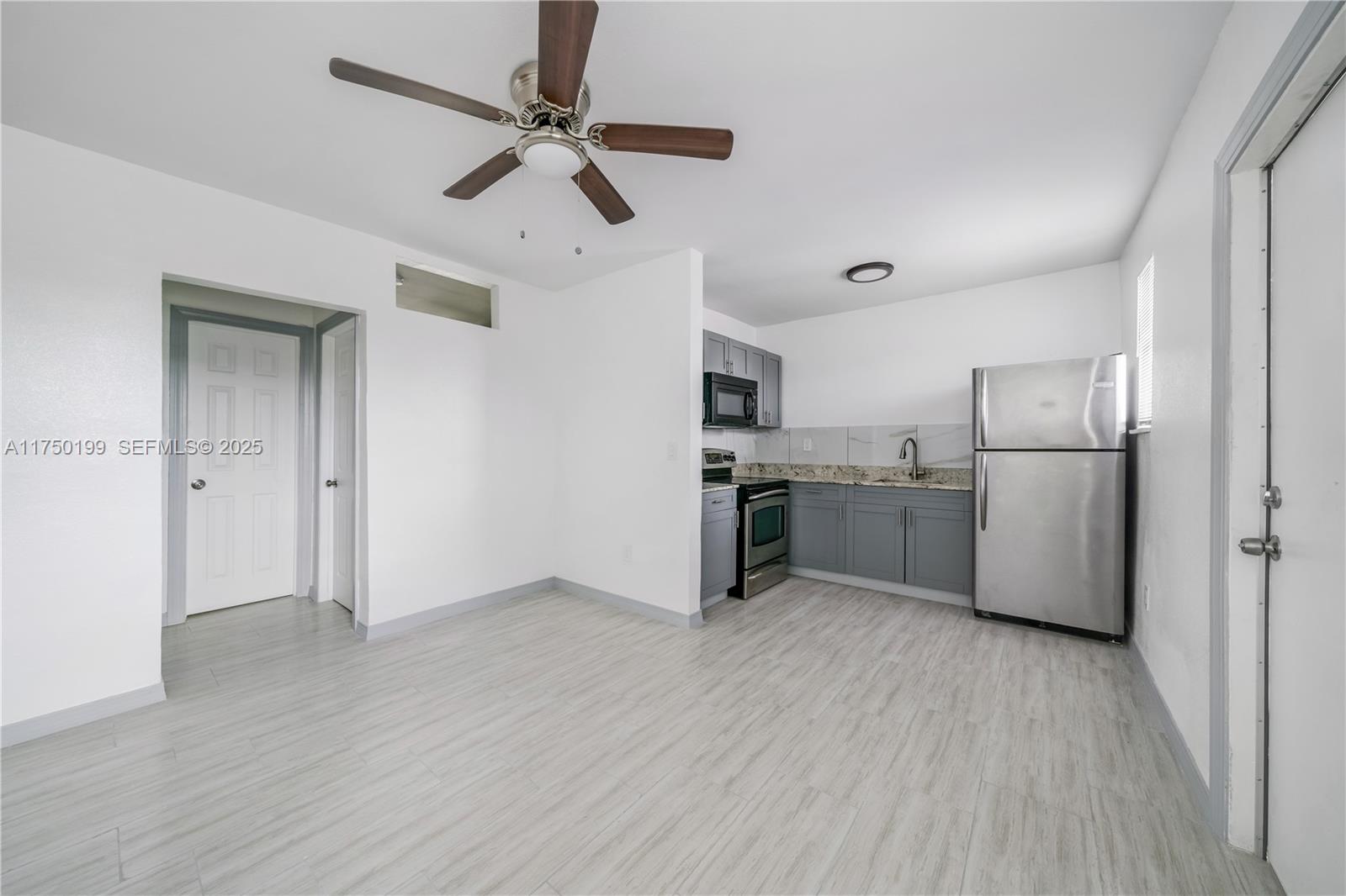 1281 Northwest 61st Street, Unit 2 Miami, FL 33142 - Photo 7 of 13 a kitchen with stainless steel appliances a refrigerator a sink dishwasher a stove and white cabinets with wooden floor