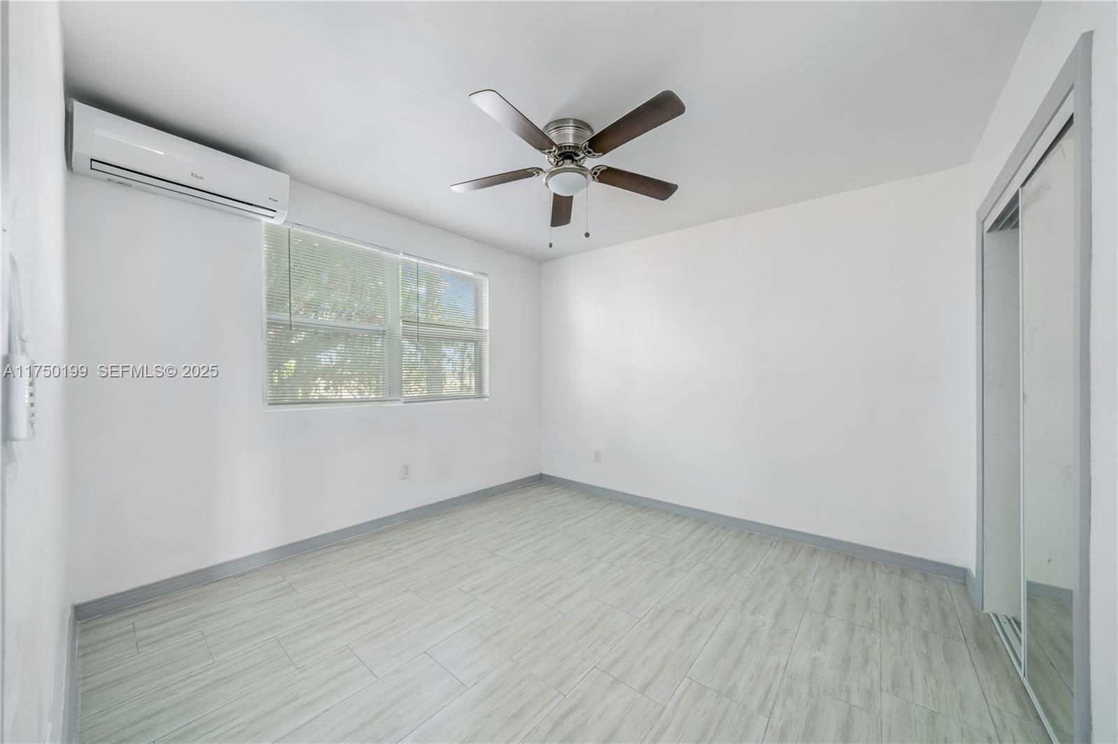 1281 Northwest 61st Street, Unit 2 Miami, FL 33142 - Photo 9 of 13 an empty room with wooden floor and windows
