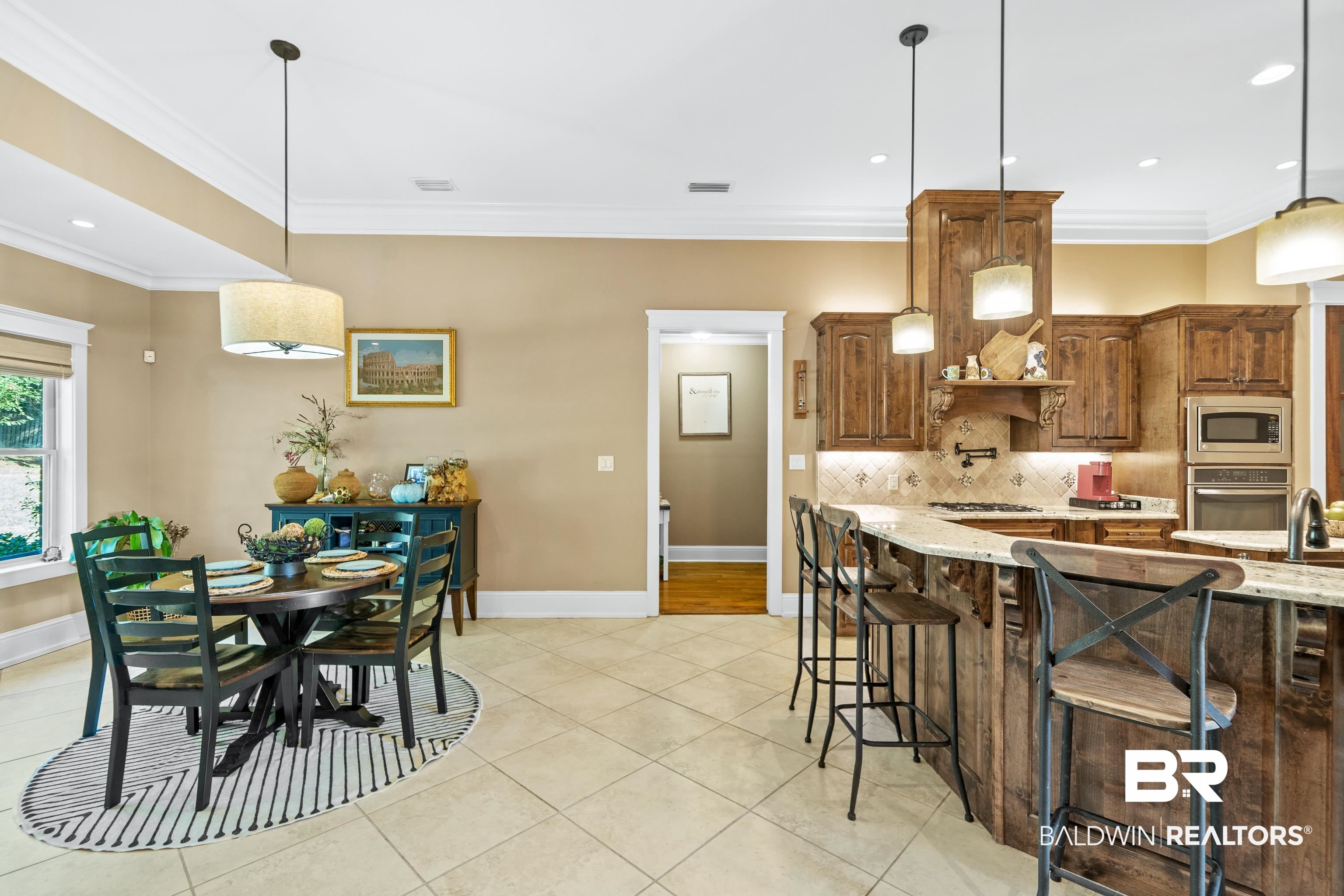 31829 Butler Drive Daphne, AL 36527 - Photo 15 of 48 Kitchen with appliances with stainless steel finishes, a breakfast bar, light stone countertops, crown molding, and decorative light fixtures