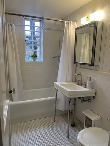 a bathroom with a sink a toilet a mirror and shower