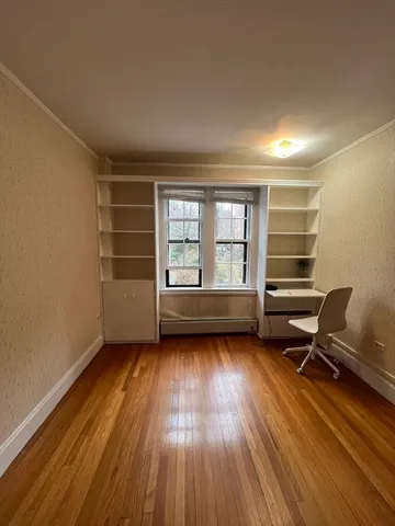 a view of a room with wooden floor a chair and a ceiling fan