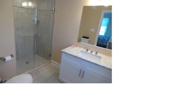 a bathroom with a sink vanity granite shower and a mirror