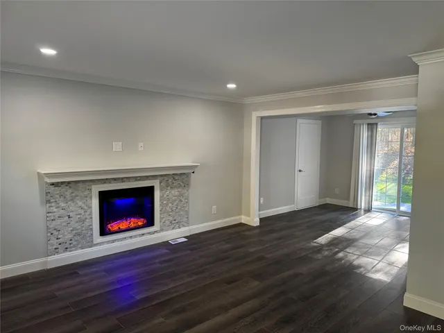 a view of an empty room with wooden floor and a fireplace