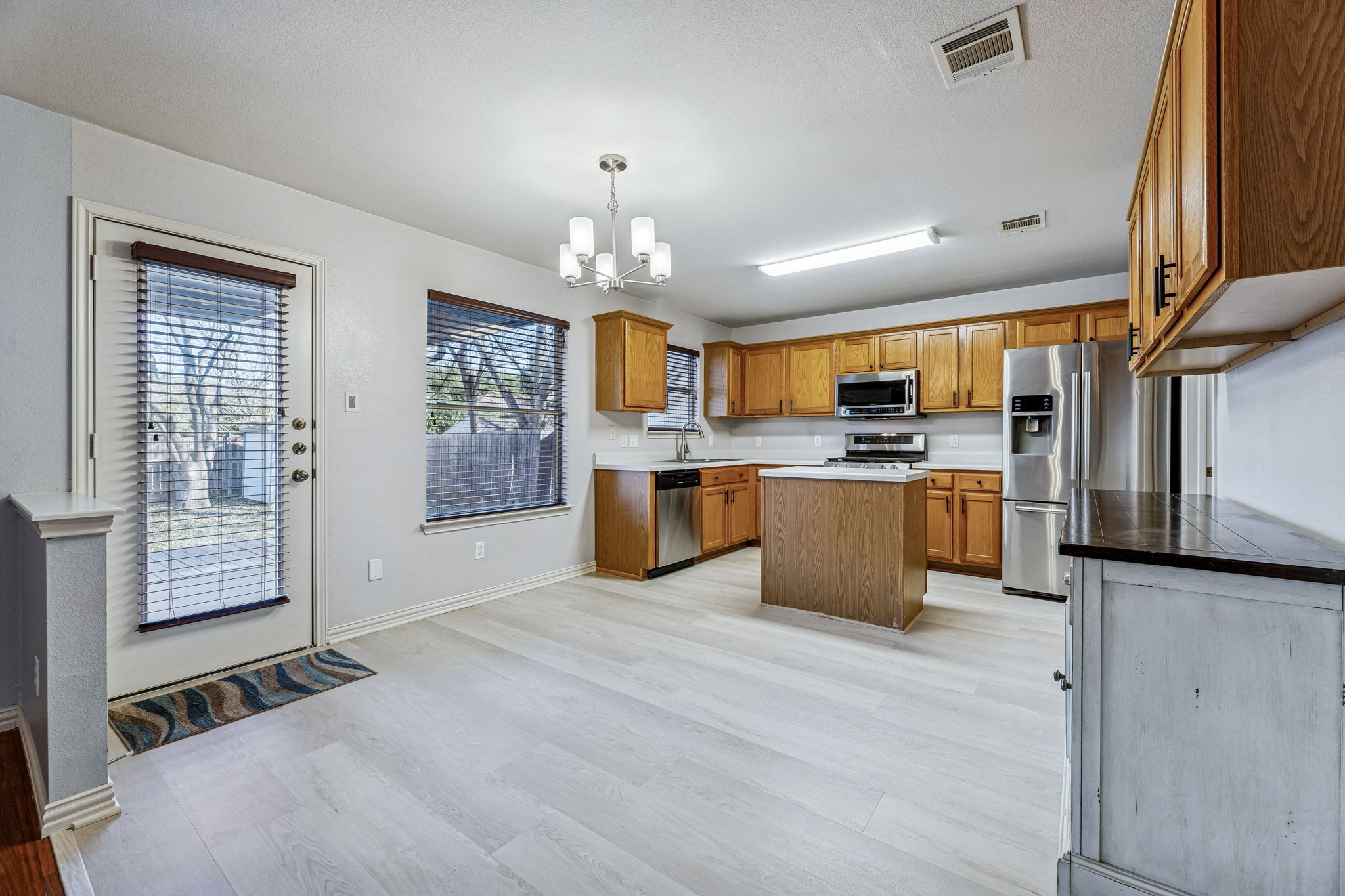 1608 Melibee Trail Austin, TX 78748 - Photo 7 of 29 Kitchen featuring wood finish cabinets, a chandelier, stainless steel appliances, a center island, and light wood-style floors
