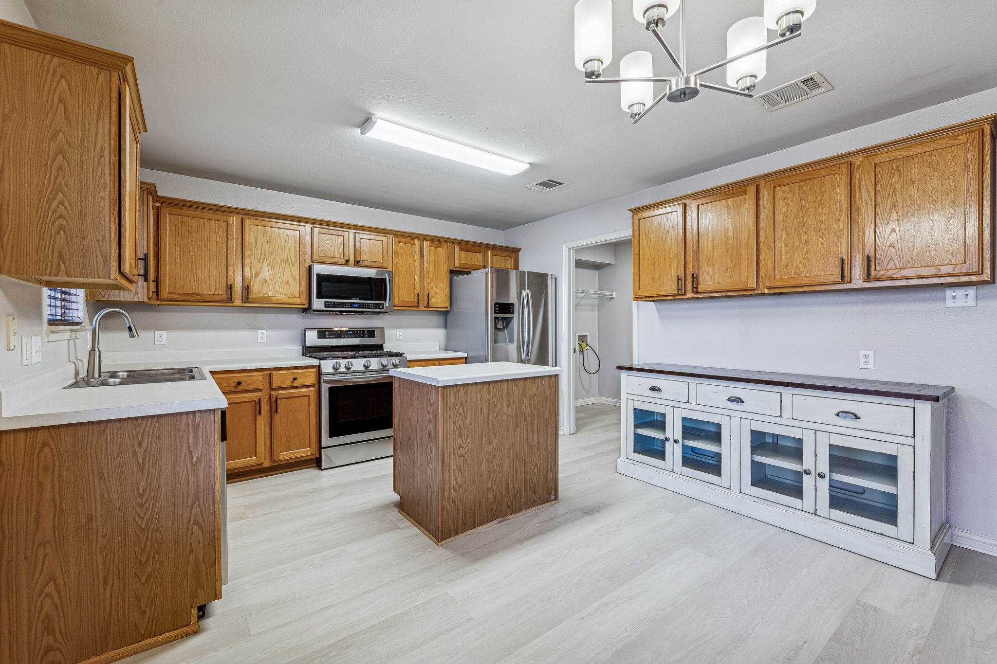 1608 Melibee Trail Austin, TX 78748 - Photo 9 of 29 Kitchen featuring wood finish cabinetry, stainless steel appliances, a kitchen island, light countertops, and light wood finished floors