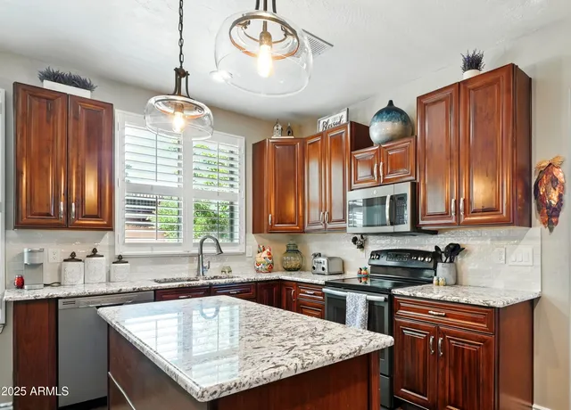 a kitchen with granite countertop a sink a counter space appliances and cabinets