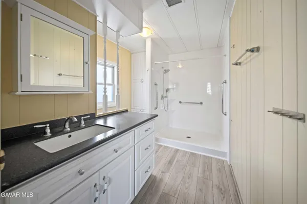 a spacious bathroom with a granite countertop sink mirror and a shower