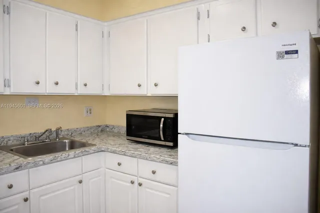a kitchen with granite countertop white cabinets and stainless steel appliances