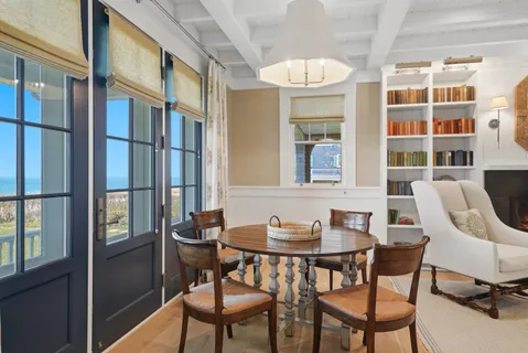 a dining room with furniture a floor to ceiling window and wooden floor