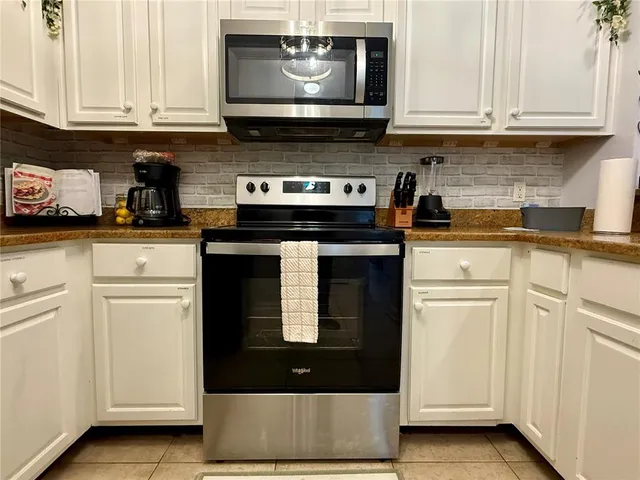 a kitchen with white cabinets and black appliances