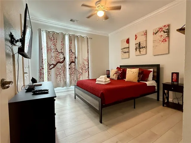 a bedroom with a bed and a flat tv screen on dresser