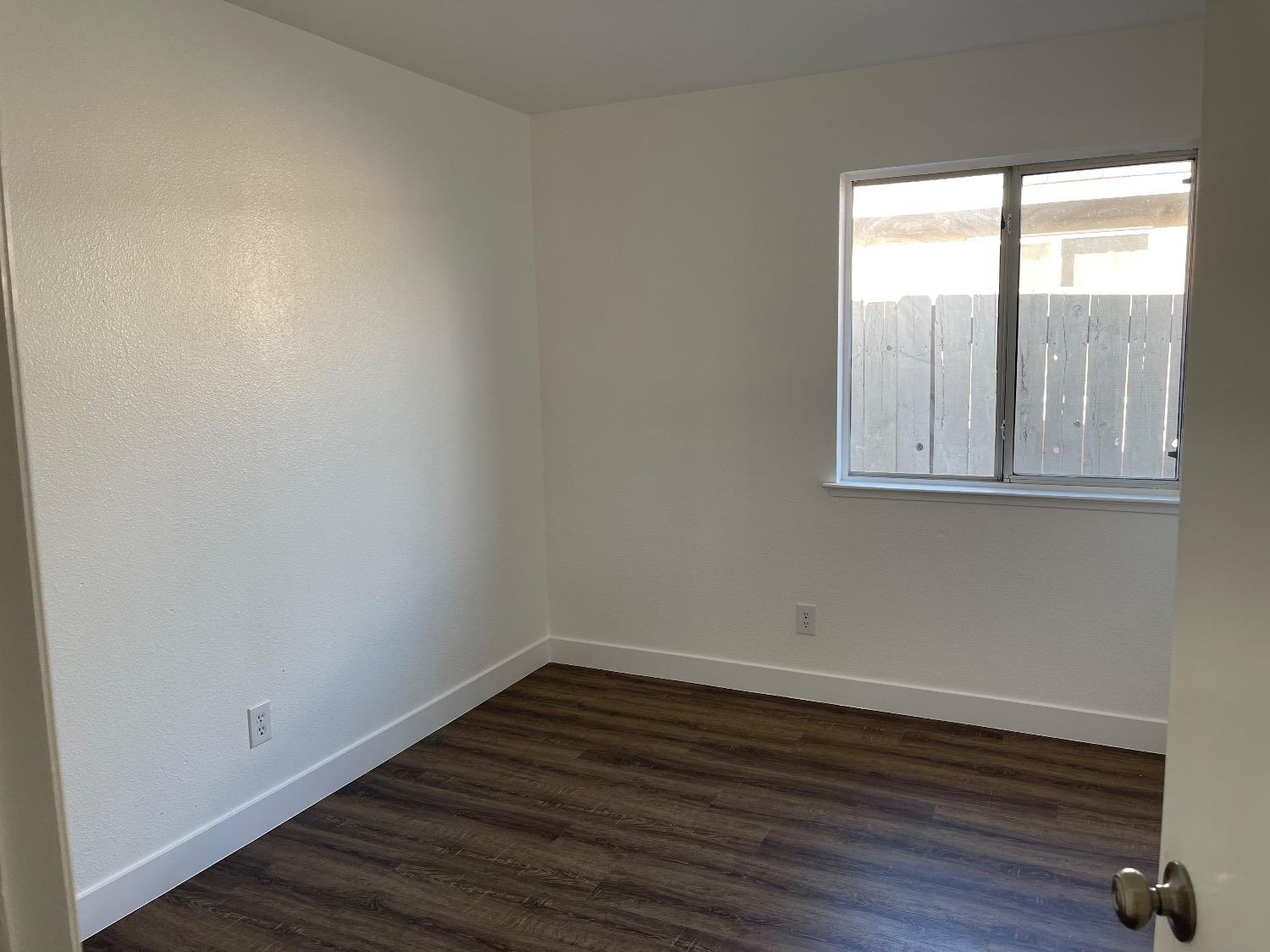 405 Fig Street Madera, CA 93638 - Photo 13 of 22 a view of an empty room with wooden floor and a window