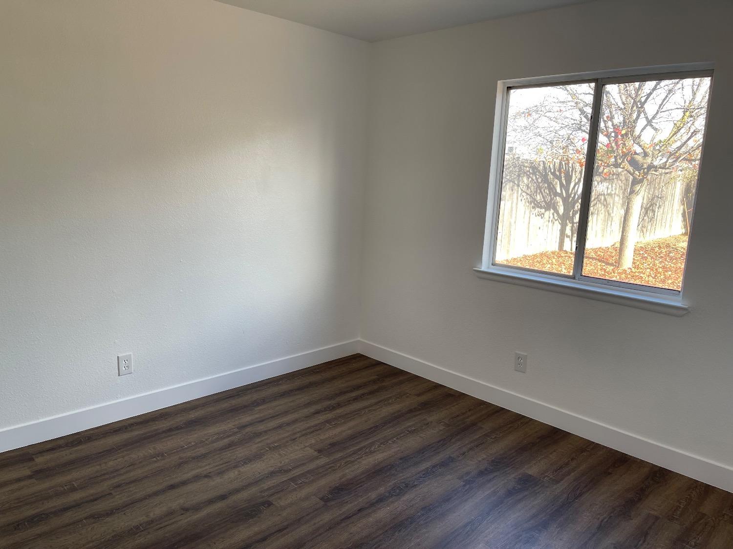 405 Fig Street Madera, CA 93638 - Photo 22 of 22 an empty room with wooden floor and windows