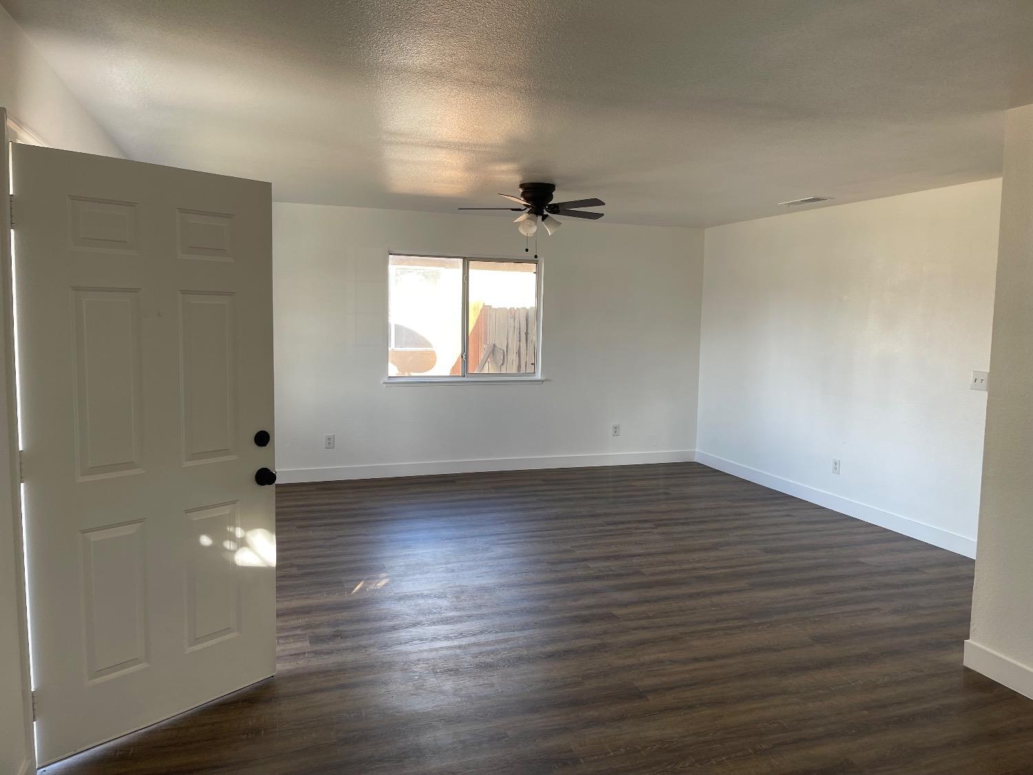 405 Fig Street Madera, CA 93638 - Photo 9 of 22 an empty room with wooden floor and windows