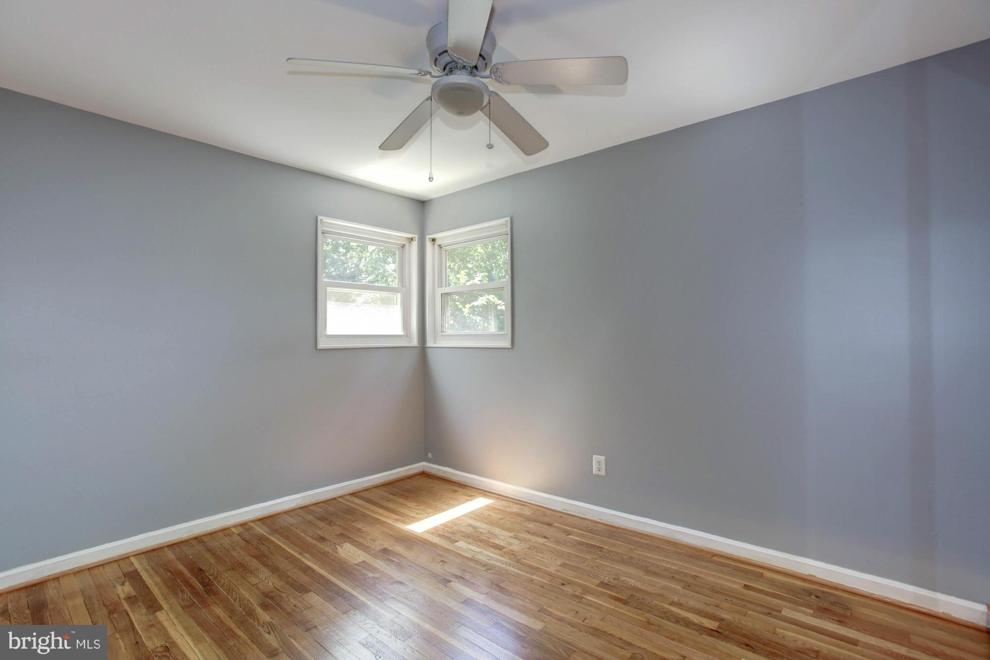 5815 Danbury Road Springfield, VA 22150 - Photo 19 of 27 an empty room with wooden floor chandelier fan and windows